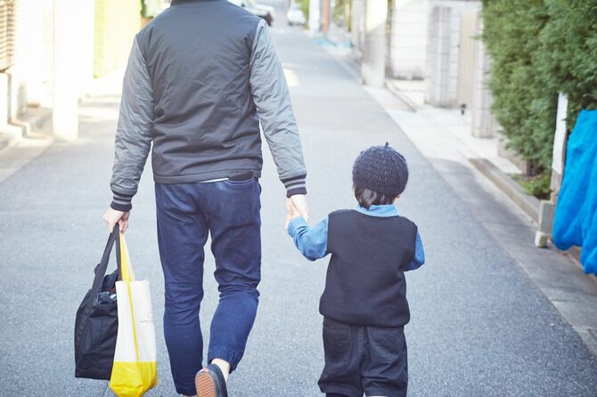 子供の手を引いて歩く父親