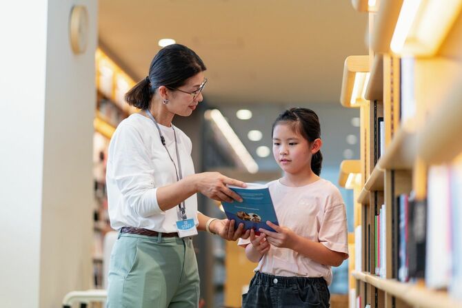 本を探す少女を手伝う司書