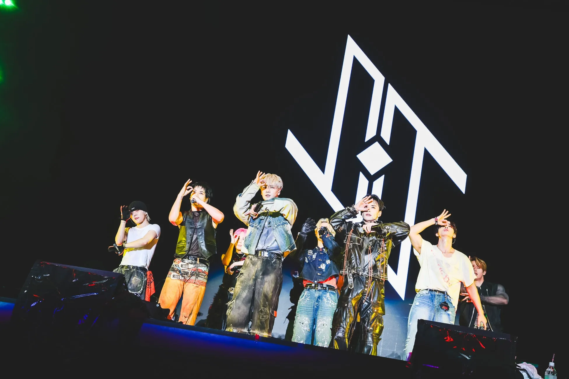 ステージでポーズをとる7人の男性グループの画像。背景は黒で、白いVITのロゴが表示されています。彼らはみな、個性的な衣装を着ています。