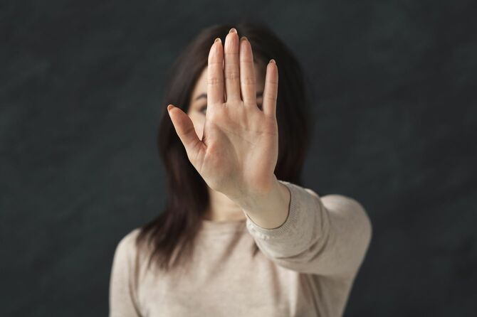 手をつきだし、拒否をジェスチャーで示している女性