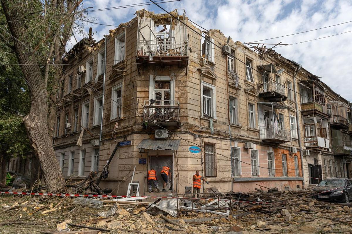 破損した住宅の横でがれきの掃除をする人たち＝１０日、ウクライナ・オデーサ/Oleksandr Gimanov/AFP/Getty Images