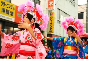 浴衣を着て、ピンクの花のデザインの帽子を被った子供たちが踊っている写真