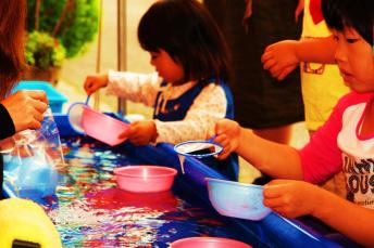 子供が左手にお椀を持って右手で金魚すくいをしている様子の写真