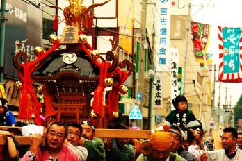 法被を着た人達が神輿を担いで歩いている様子の写真