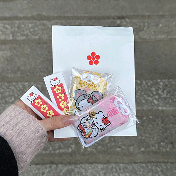 京都・吉祥院天満宮で手に入るキティちゃんのおみくじやお守りを手にした写真