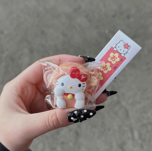 京都・吉祥院天満宮で販売の、キティちゃんがさるを被っているマスコットを手に持つ写真