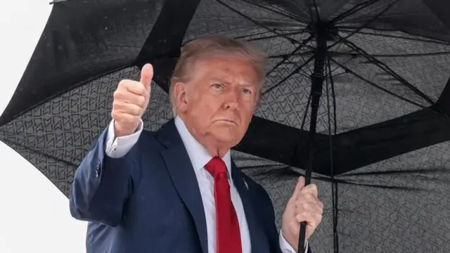 エアフォース・ワン搭乗前に傘を差しながら親指を立てるドナルド・トランプ氏