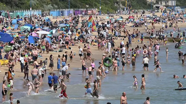 イングランド南部ボーンマスのビーチで、多くの人が海に入ったり、砂浜で日光浴をしたりしている。ビーチパラソルも点在している