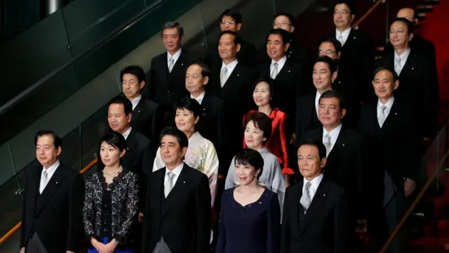 第2次安倍改造内閣発足後、首相官邸の階段で、記念写真に納まる高市氏。黒いドレスを着て、最前列の安倍氏と麻生氏の間に立って微笑んでいる