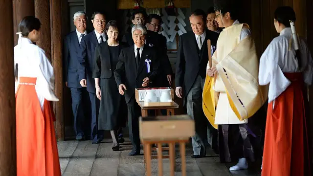 靖国神社の神官や巫女たちを前に、ダークスーツで並ぶ閣僚たち